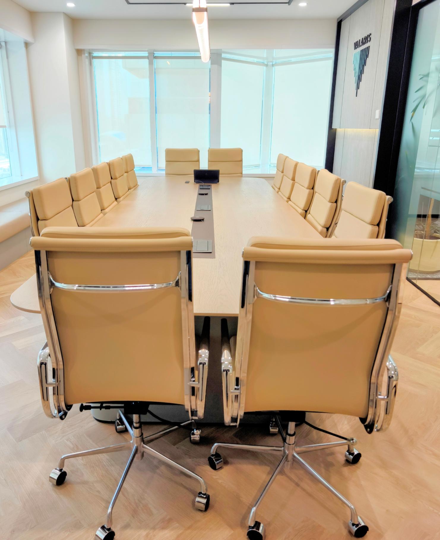 Modern conference room with glass works in Dubai featuring beige leather chairs and wooden flooring at Valaris office